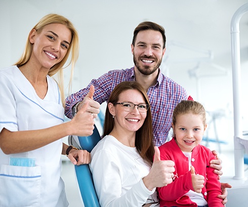 Family of three posing with dental team member