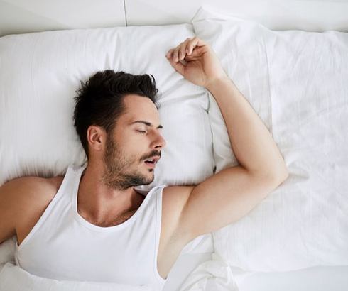 Man snoring in bed with mouth open
