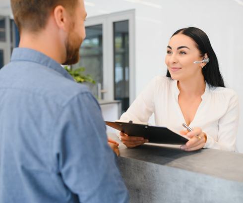 Patient talking with person behind dental office front desk