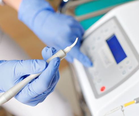 Gloved hand preparing to use dental laser
