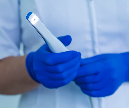 Two gloved hands holding an intraoral camera