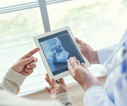 Dentist showing a patient scans of their jaw on tablet screen