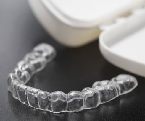 Invisalign clear aligner next to its carrying case