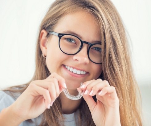 Smiling young woman holding Invisalign in Portland