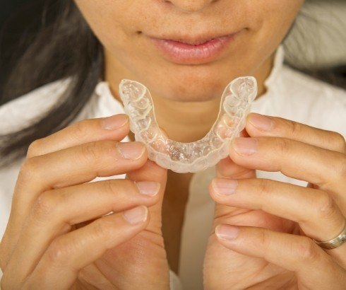 Close up of person holding an Invisalign clear aligner