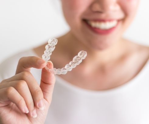Smiling person holding an Invisalign tray