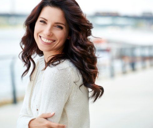 Woman in white sweater smiling outdoors