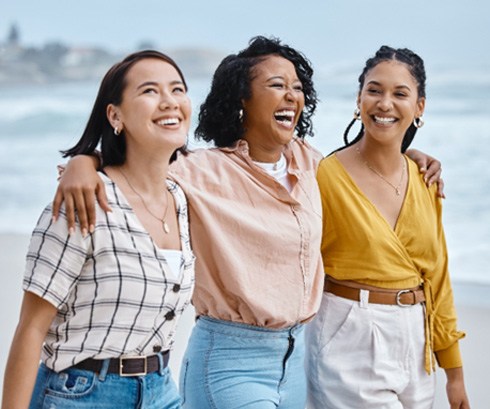 Happy group of friends walking on the beach