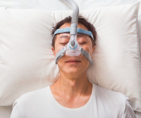 Sleeping man wearing C P A P machine for sleep apnea treatment