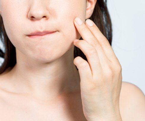 Close up of person holding their jaw in pain