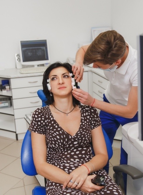 Dentist placing T M J sonogram on sides of a patient's head