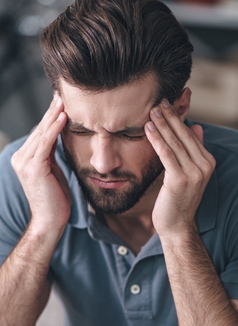 Man touching both his temples in frustration