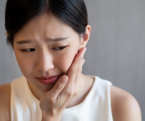 Woman holding side of her face in pain
