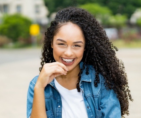 Young woman in denim shirt smiling with traditional braces