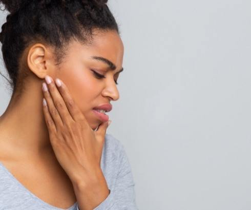 Side view of woman touching her jaw in pain