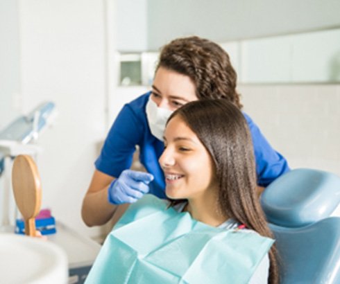 Orthodontic assistant pointing to patient smiling with braces