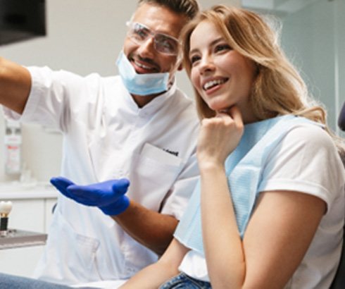Orthodontist and patient smiling while looking at screen
