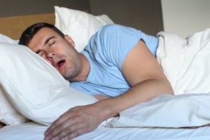 Snoring man fast asleep in bed in need of sleep apnea treatment