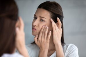 Woman looking in mirror, noticing signs of aging