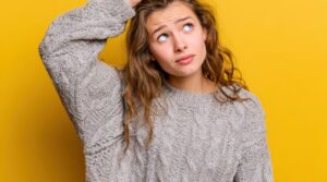 Young woman with worried expression, scratching her head