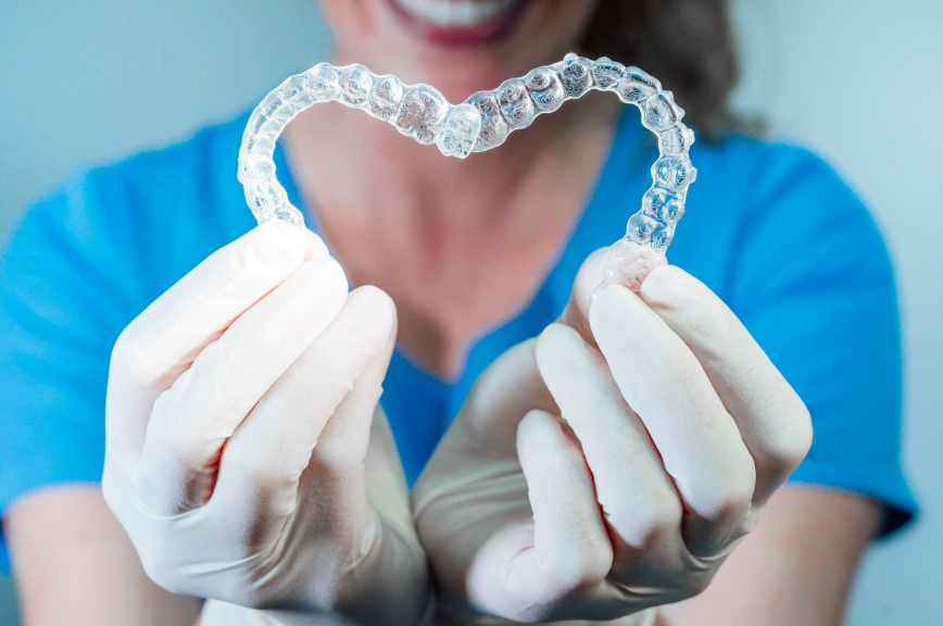 Dentist holding clear aligners in heart shape